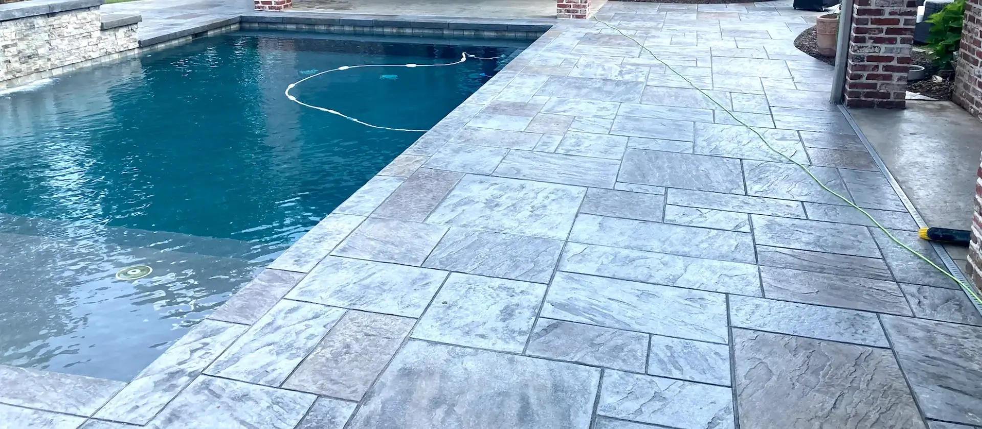 A pool with a tile floor and a stone wall.